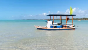 Barco de passeio parado nas águas rasas e cristalinas de Maragogi em dia ensolarado.